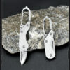 A small keychain knife displayed leaning against a rock.