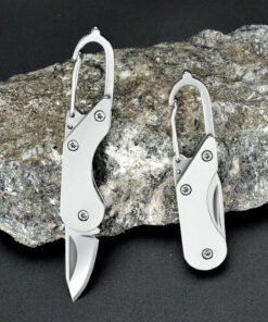A small keychain knife displayed leaning against a rock.