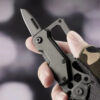 A man's hand holding a small multitool knife.