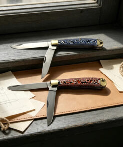 Two folding trapper knife models of differing colors displayed with their twin blades opened.