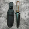A hori hori garden knife tool, displayed next to its sheath.