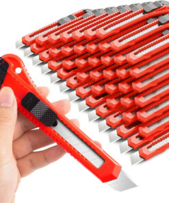 A man's hand holding a snap off utility knife, with a bulk pile of utility box cutter knives in the background.