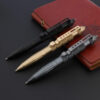 Three tactical pen self defense models of differing colors displayed leaning against a leather wallet.