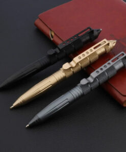 Three tactical pen self defense models of differing colors displayed leaning against a leather wallet.