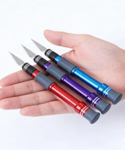 A mans's hand hold three craft knife models of differfing colors.
