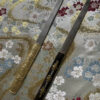 Two Kogatana small Japanese knife models displayed against silk cloth.