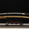 A Longquan tiger Katana sword, displayed on a small wooden stand, alongside its scabbard.
