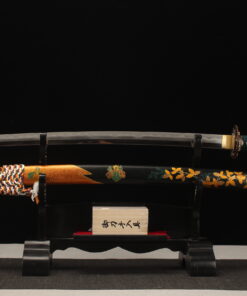 A folded steel sword Katana, displayed on a small wooden stand, alongside its scabbard.