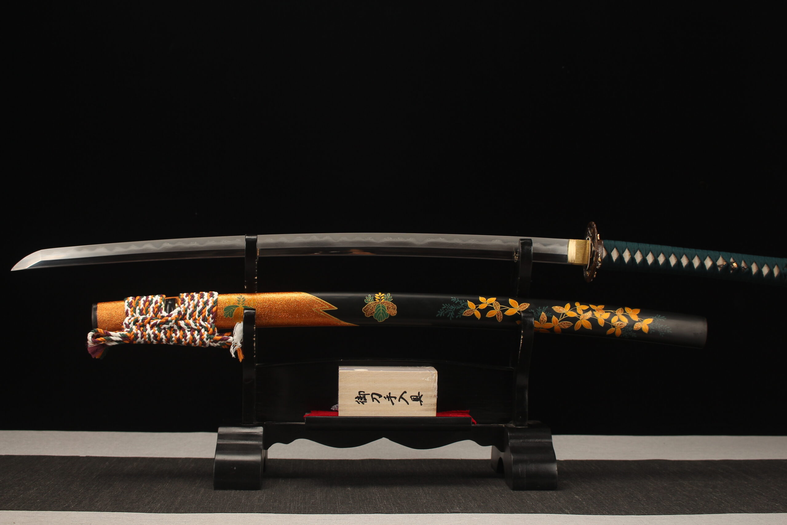 Steel Sword A folded steel sword Katana, displayed on a small wooden stand, alongside its scabbard.