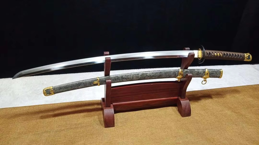 Tamahagane Katana A hand forged Tamahagane Katana, displayed on a woden stand, alongside its scabbard.